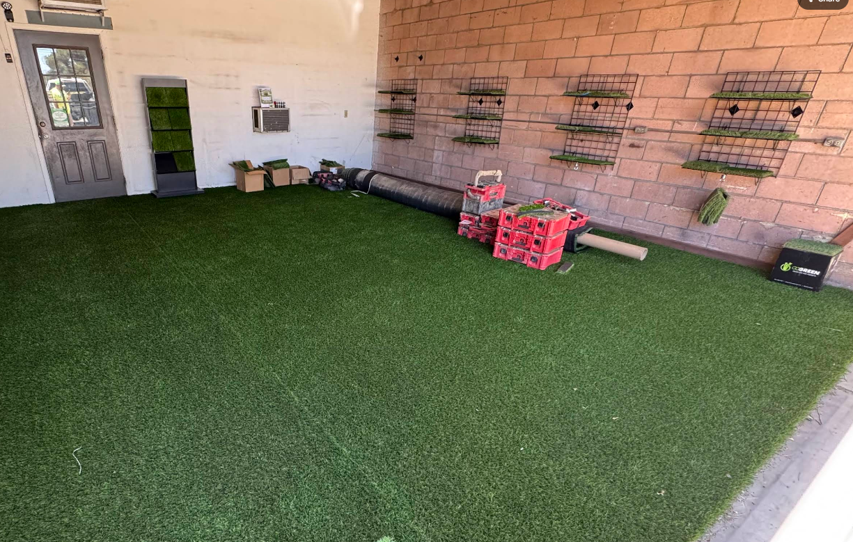 Covered patio with artificial turf, brick wall shelves, and a few red planter boxes.