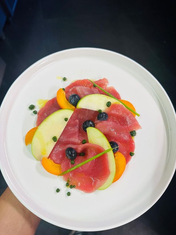 Piatto di frutta da dessert con pesche, prugne e mirtilli a fette su un piatto bianco.