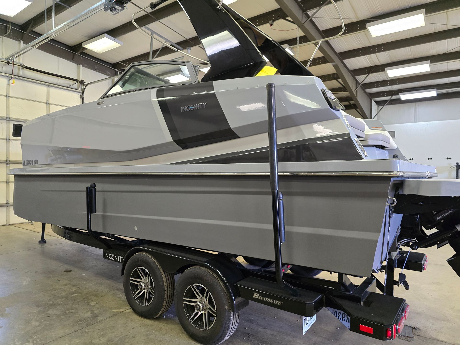 A gray boat is parked on a trailer in a garage.