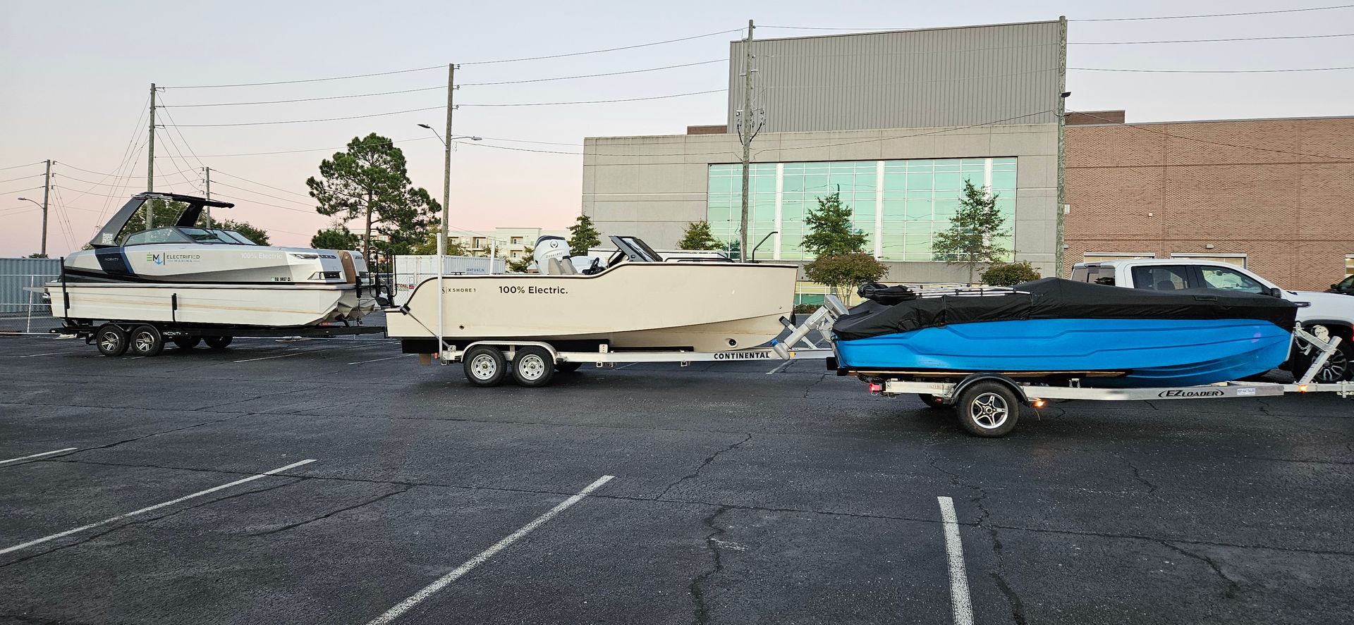 A boat is being towed by a truck in a parking lot