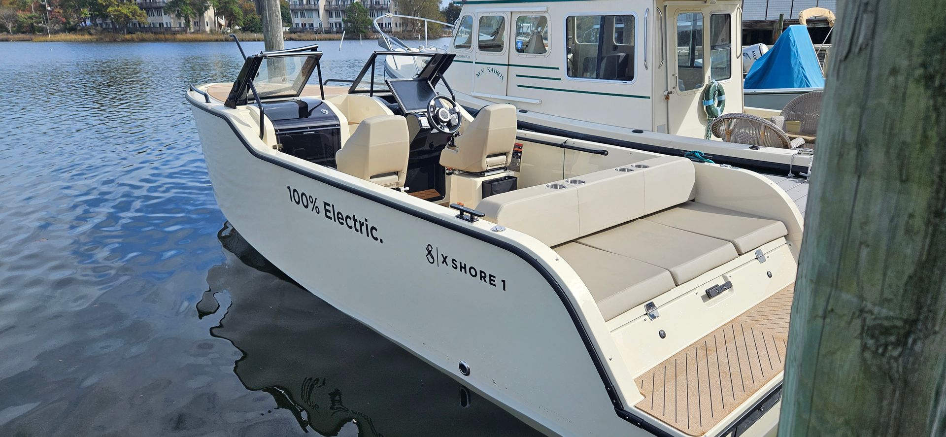 A small white boat is docked in the water near a dock.