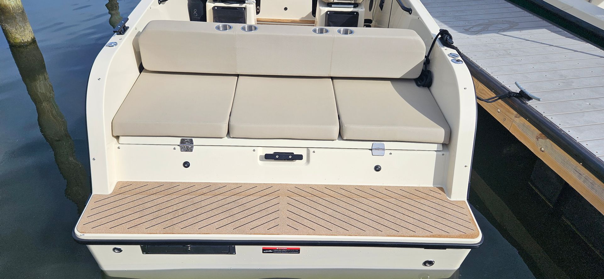 A white boat is docked at a dock with a cushioned seat.