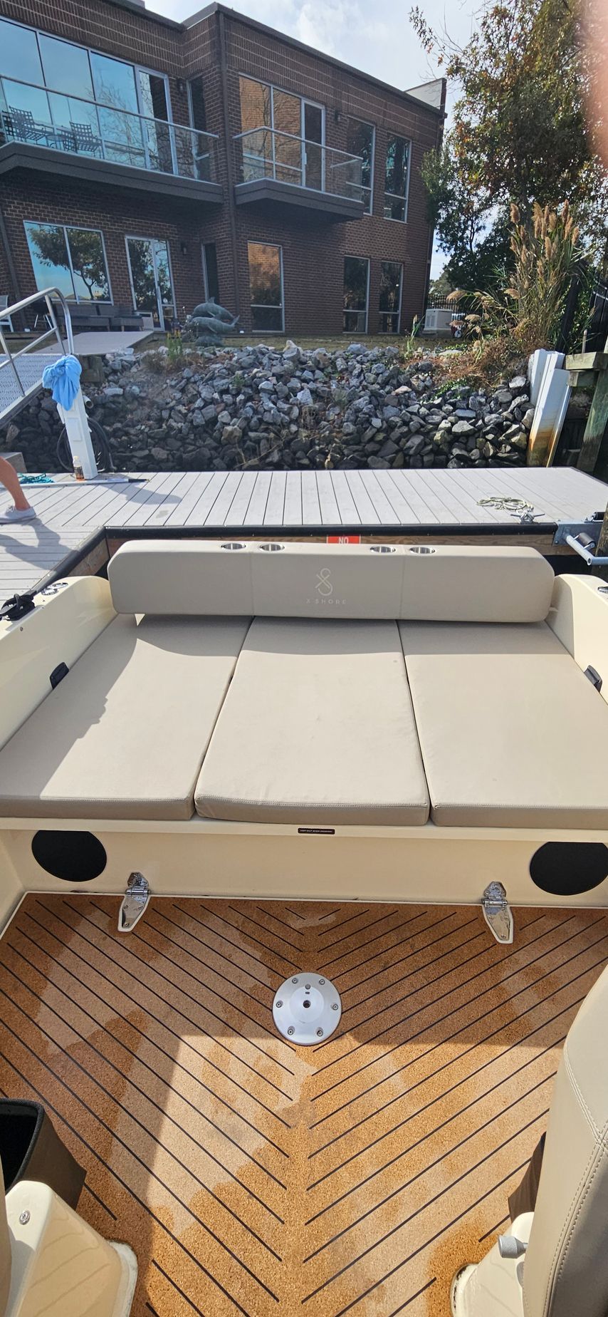 The back of a boat with a wooden deck and a couch.