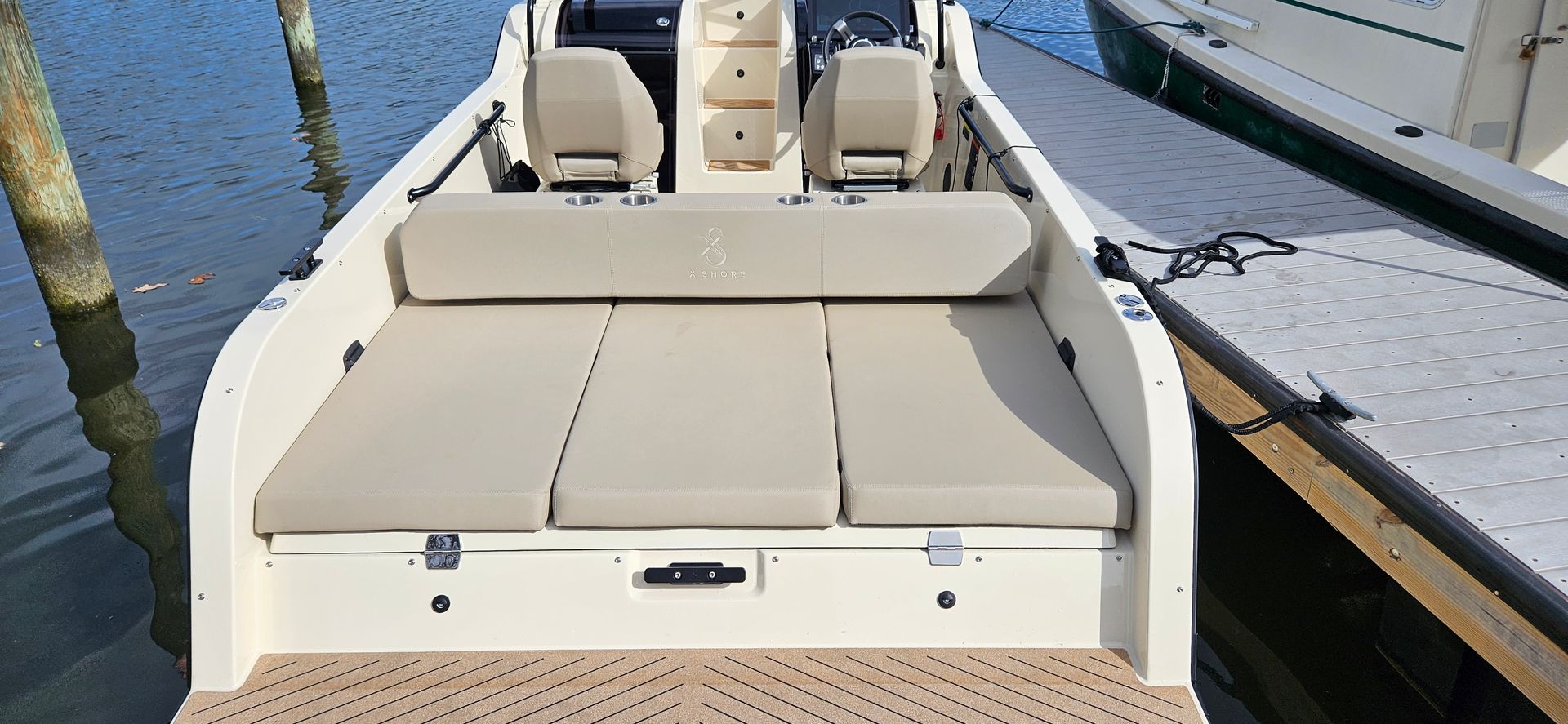 A white boat is docked at a dock next to a body of water.