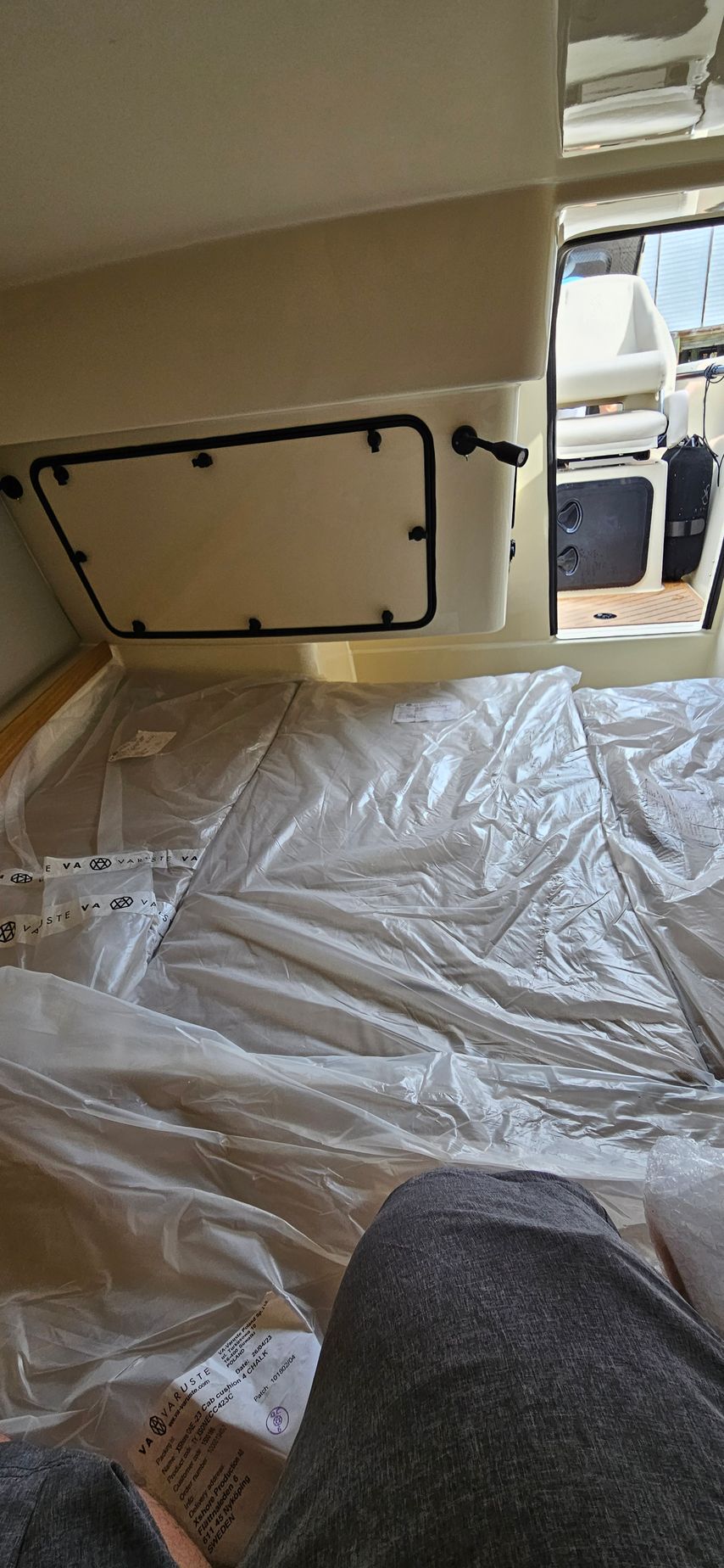 A person is sitting on a bed in a boat covered in plastic.