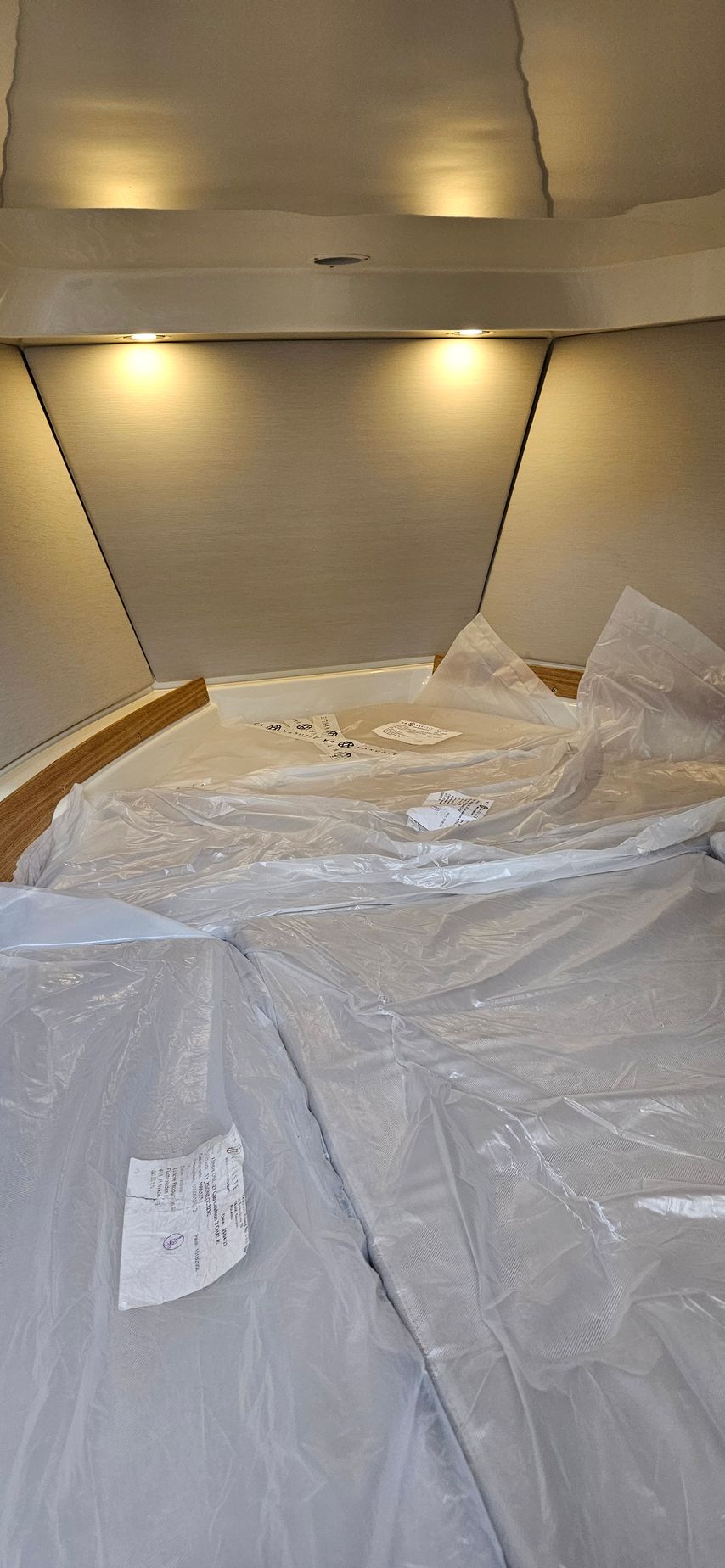 A bed is covered in plastic wrap in a room.
