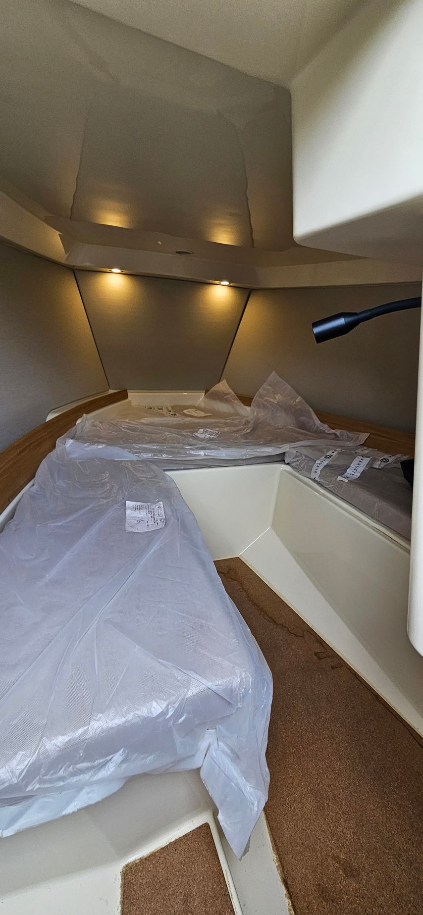 The inside of a boat with a bed and a table covered in plastic.
