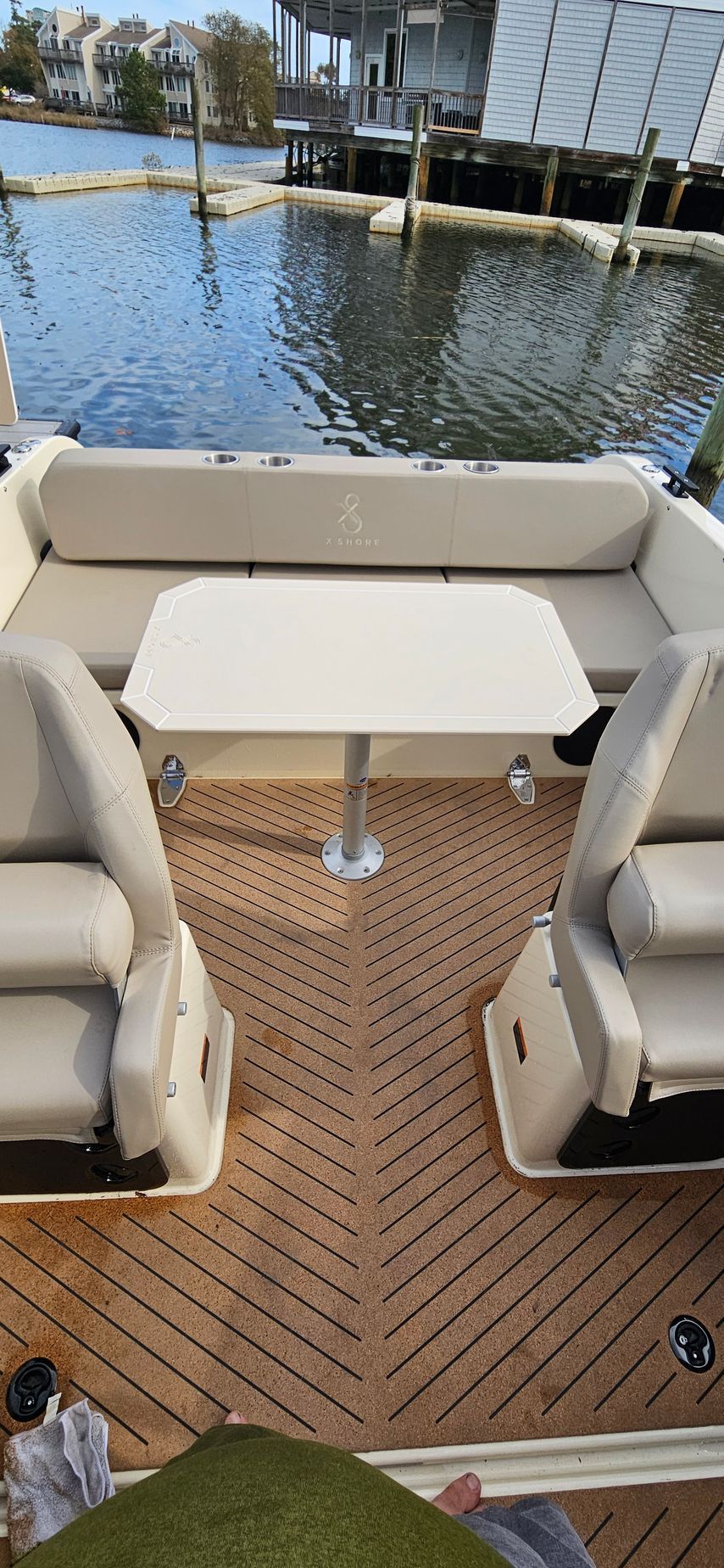 The back of a boat with a table and chairs in the water.