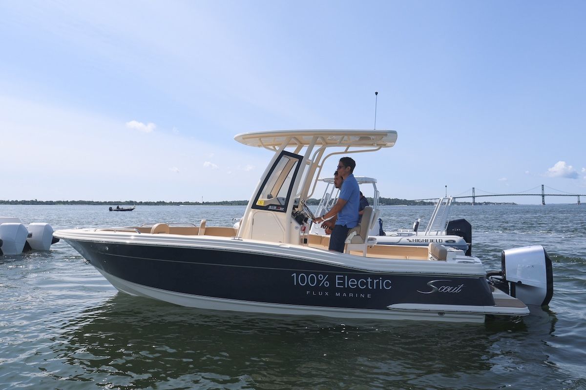 a black pontoon with two seats in the front around the deck of the pontoon with the canopy up there are three people on board