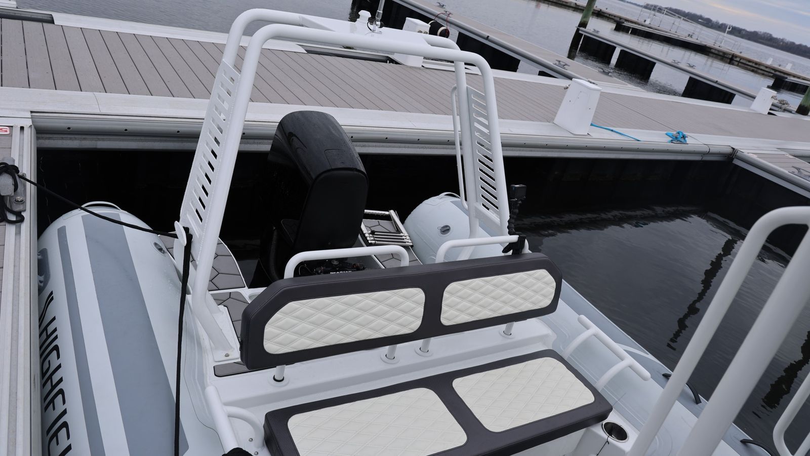 A white boat is docked at a dock in the water.