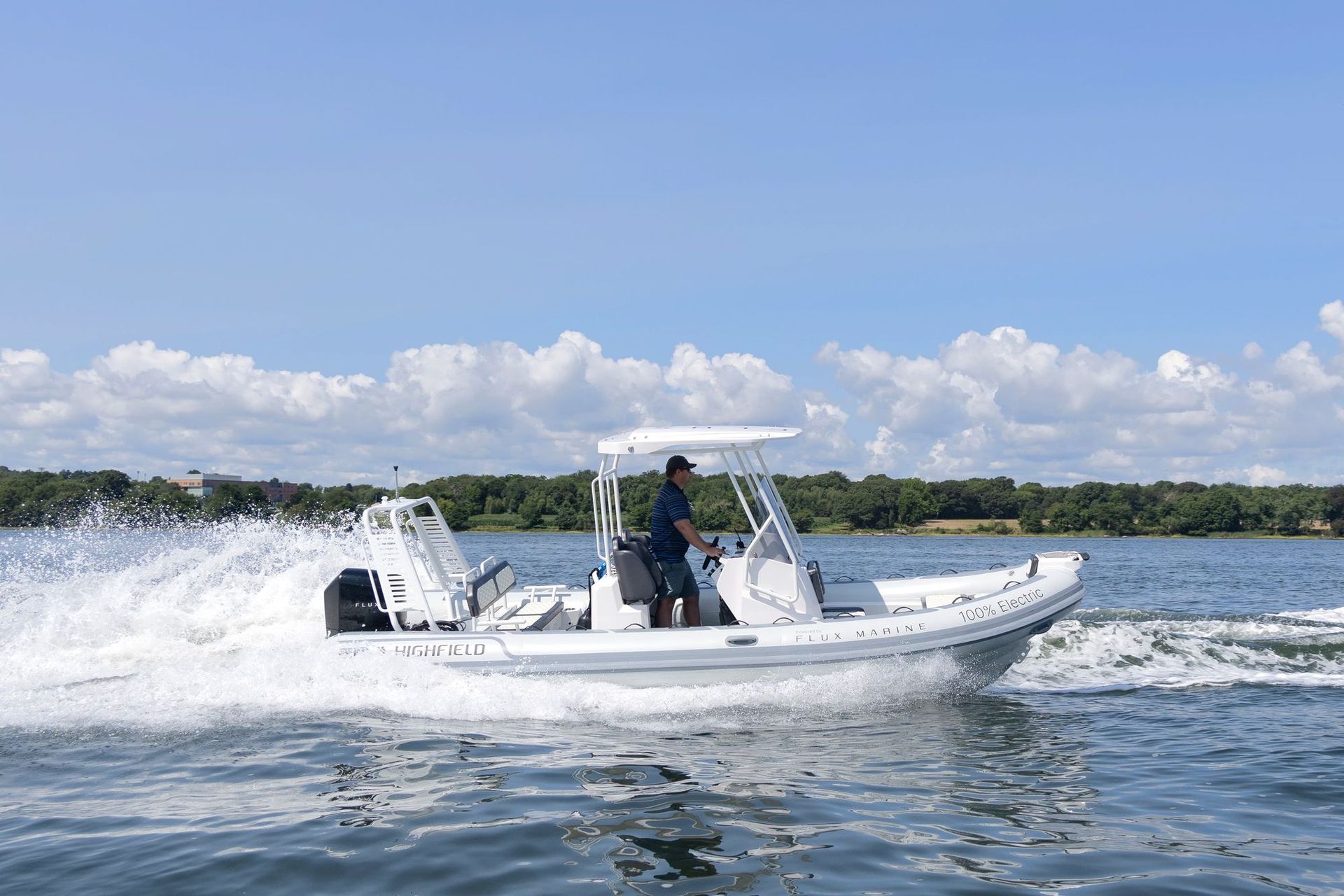A man is driving a white boat on a lake.