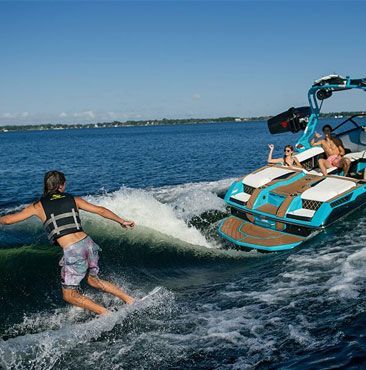 A man is being towed by a boat while riding a wave.