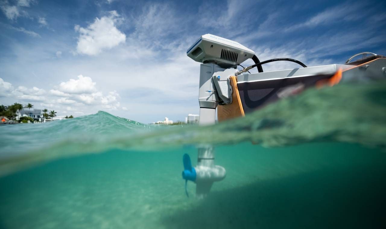 propeller of the motor in the water and the rest of the motor attached to a small boat