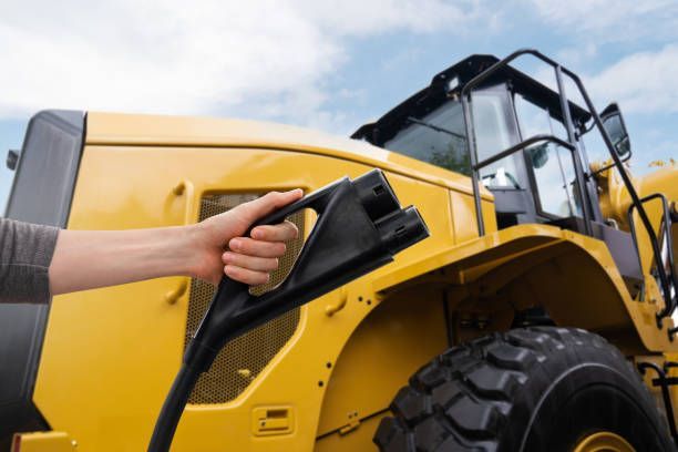 A person is holding the handle of a yellow tractor.