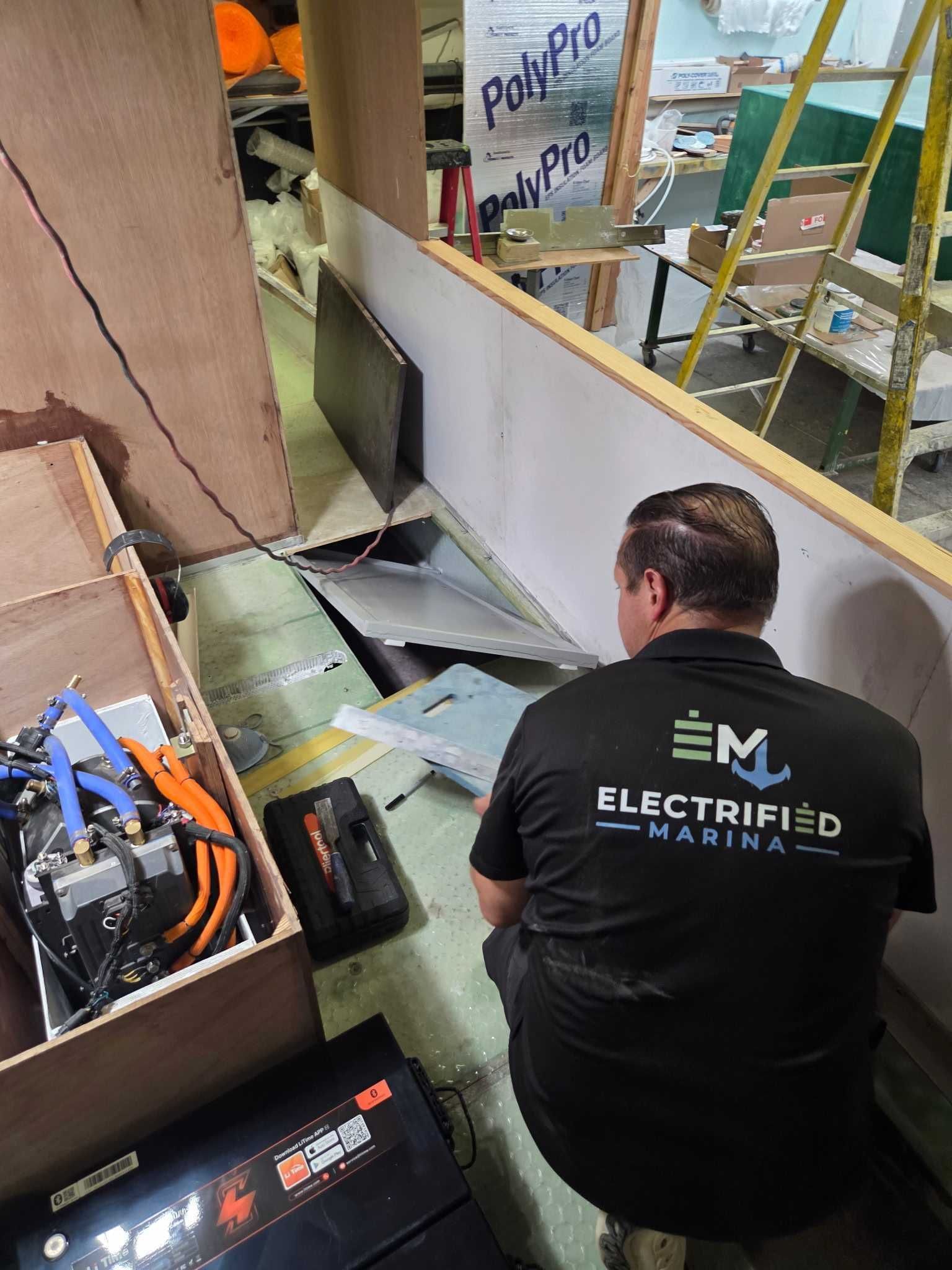 Electrified Marina technician working on installation of boat being built in warehouse