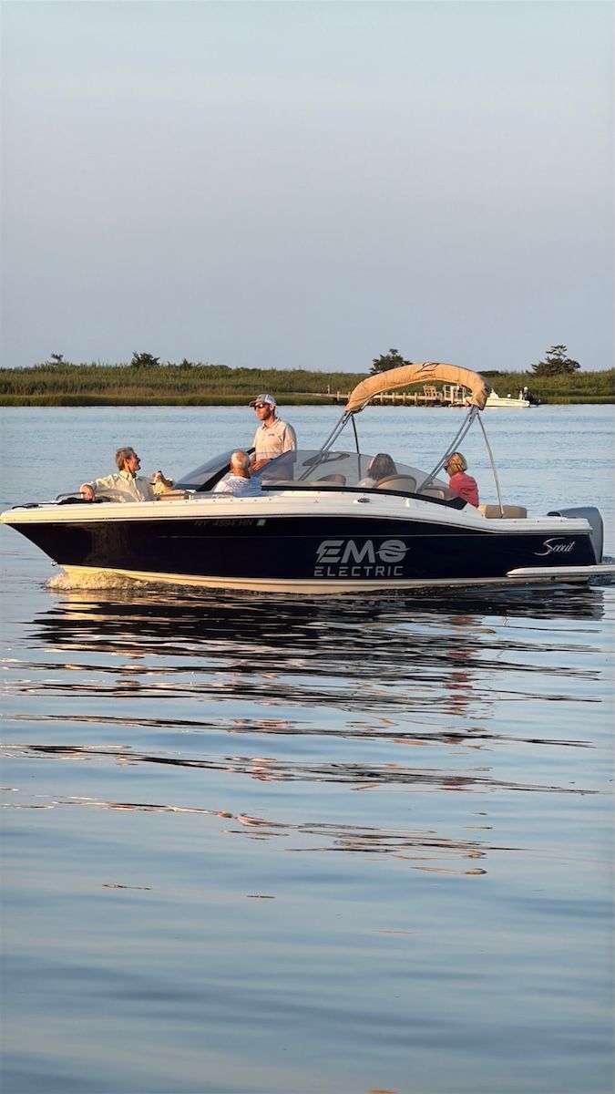 a black pontoon with two seats in the front around the deck of the pontoon with the canopy up there are three people on board