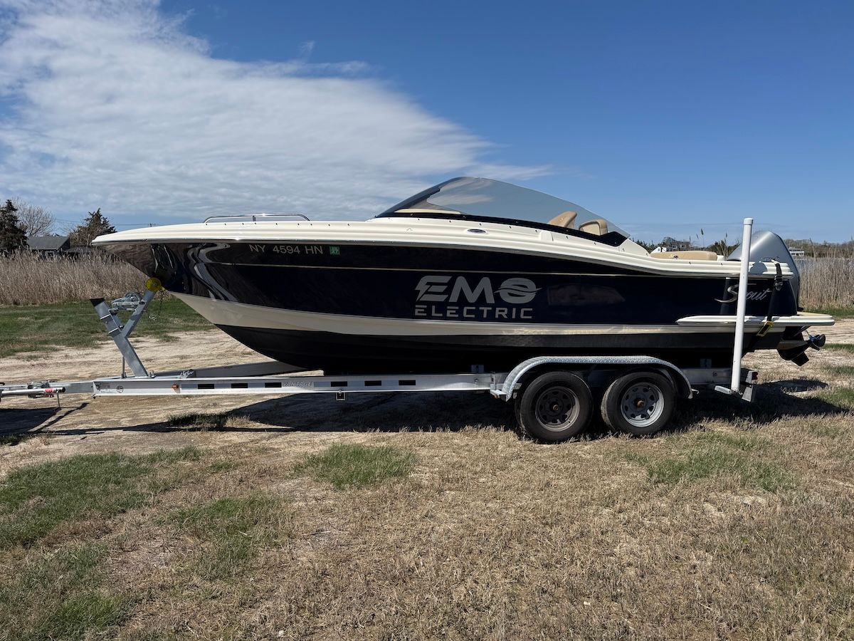 a blue scout dorado with EMO Electric decal on the side is sitting on a trailer in the grass 