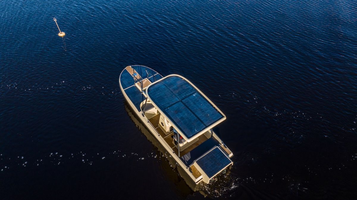Amber from Elvene moving slowly in blue water going north west. The boat is covered in solar panels.