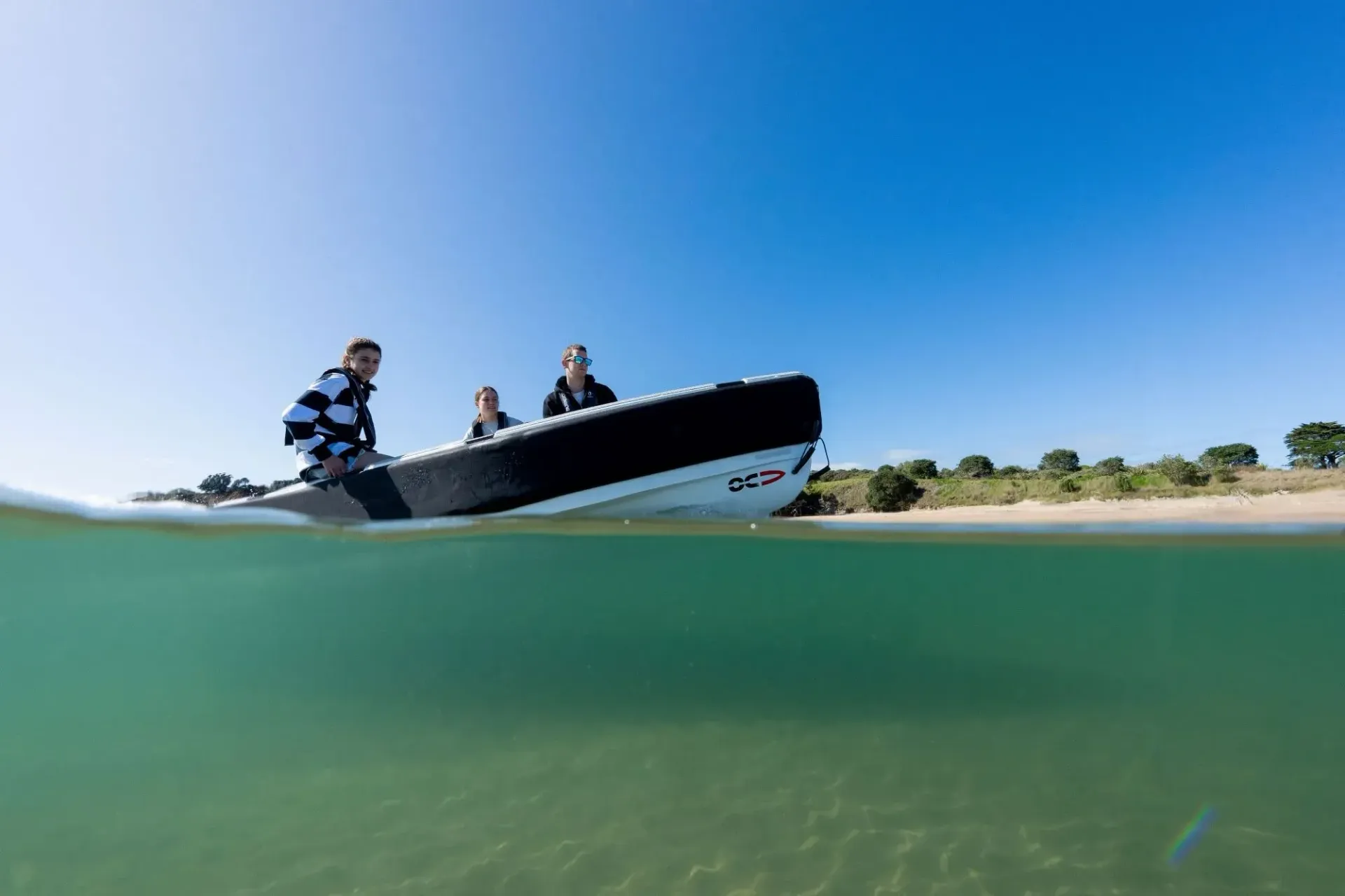 three people on a small tender in the water sitting idle