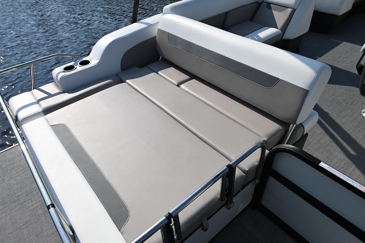 Sunbed on the back (stern) of a pontoon boat beige cushion color and railngs along the side of the sunbed