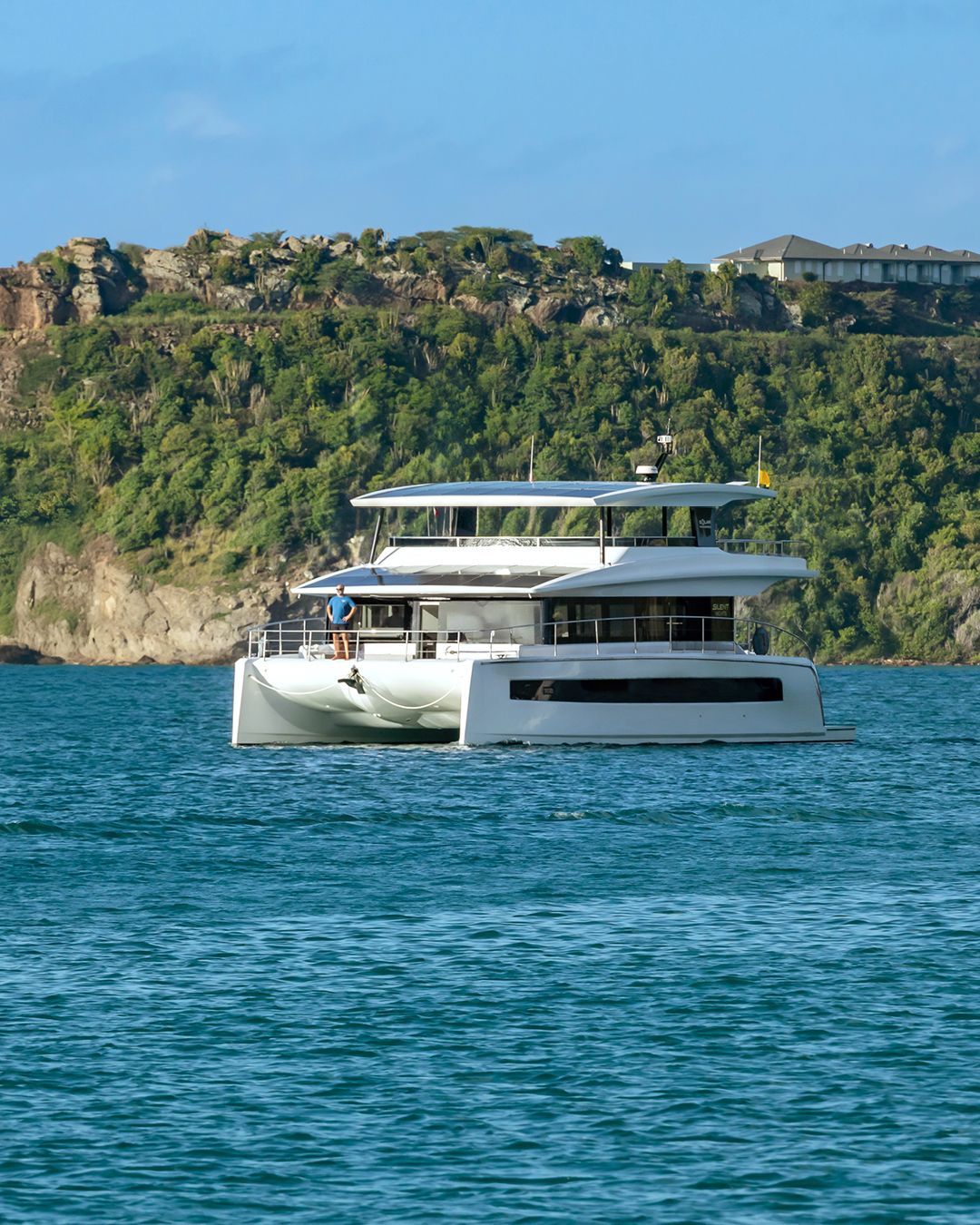 3 deck yacht in blue water and green foliage in background