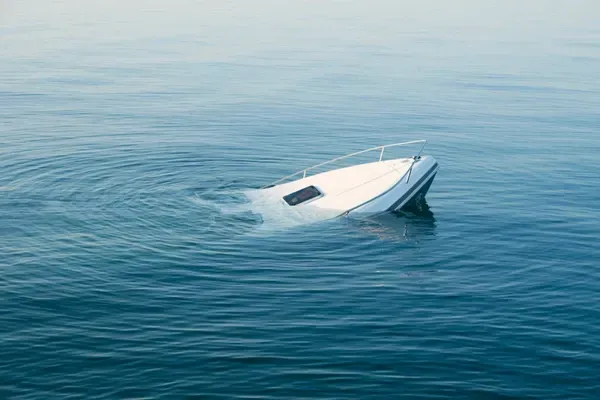 A boat is floating on its side in the ocean.