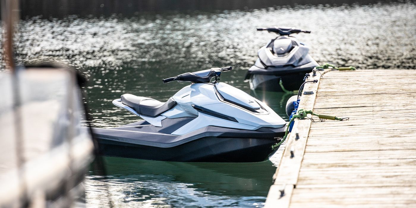 two white jet skis ties up at dock 