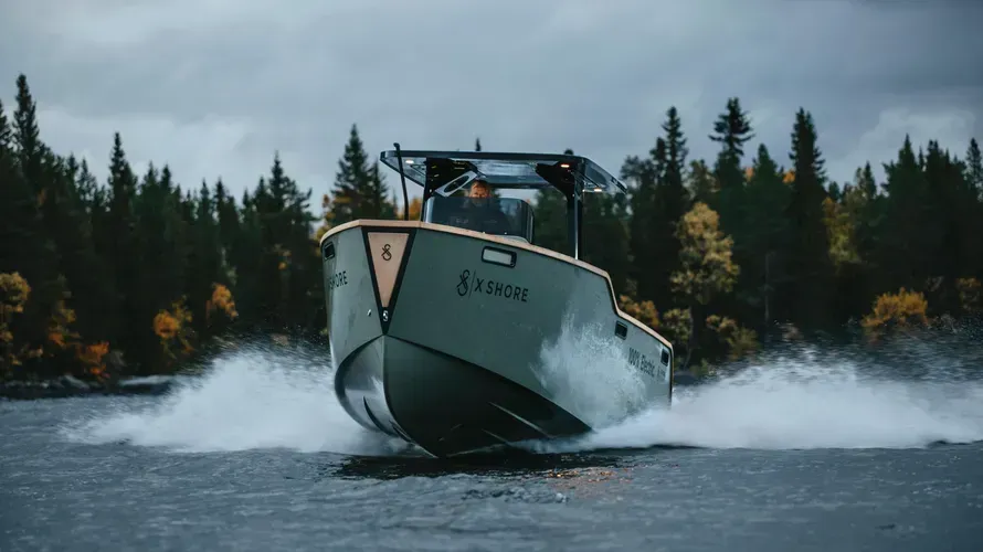 A boat is floating on top of a lake with trees in the background.