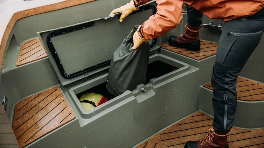 A person is taking a bag out of a boat trunk.