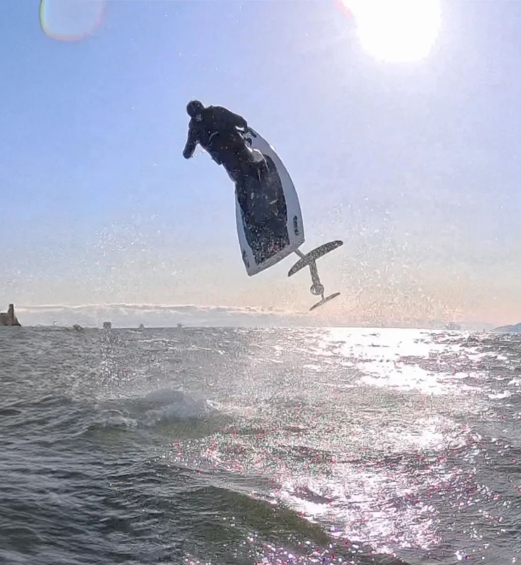 A person is flying through the air while riding a surfboard in the ocean.