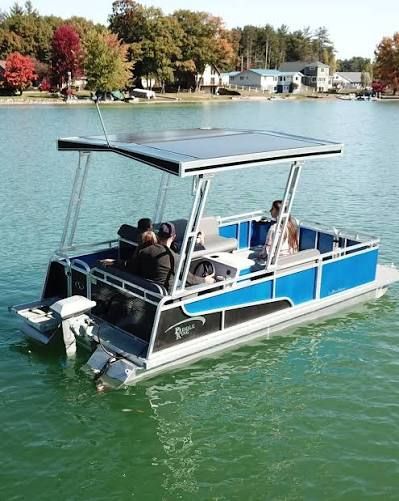 A man and woman are riding a pontoon boat on a lake.