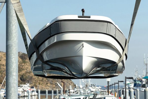 Carbon white boat with grey accent is lifted on forklift at a dock the picture shows the boat facing the bow head on