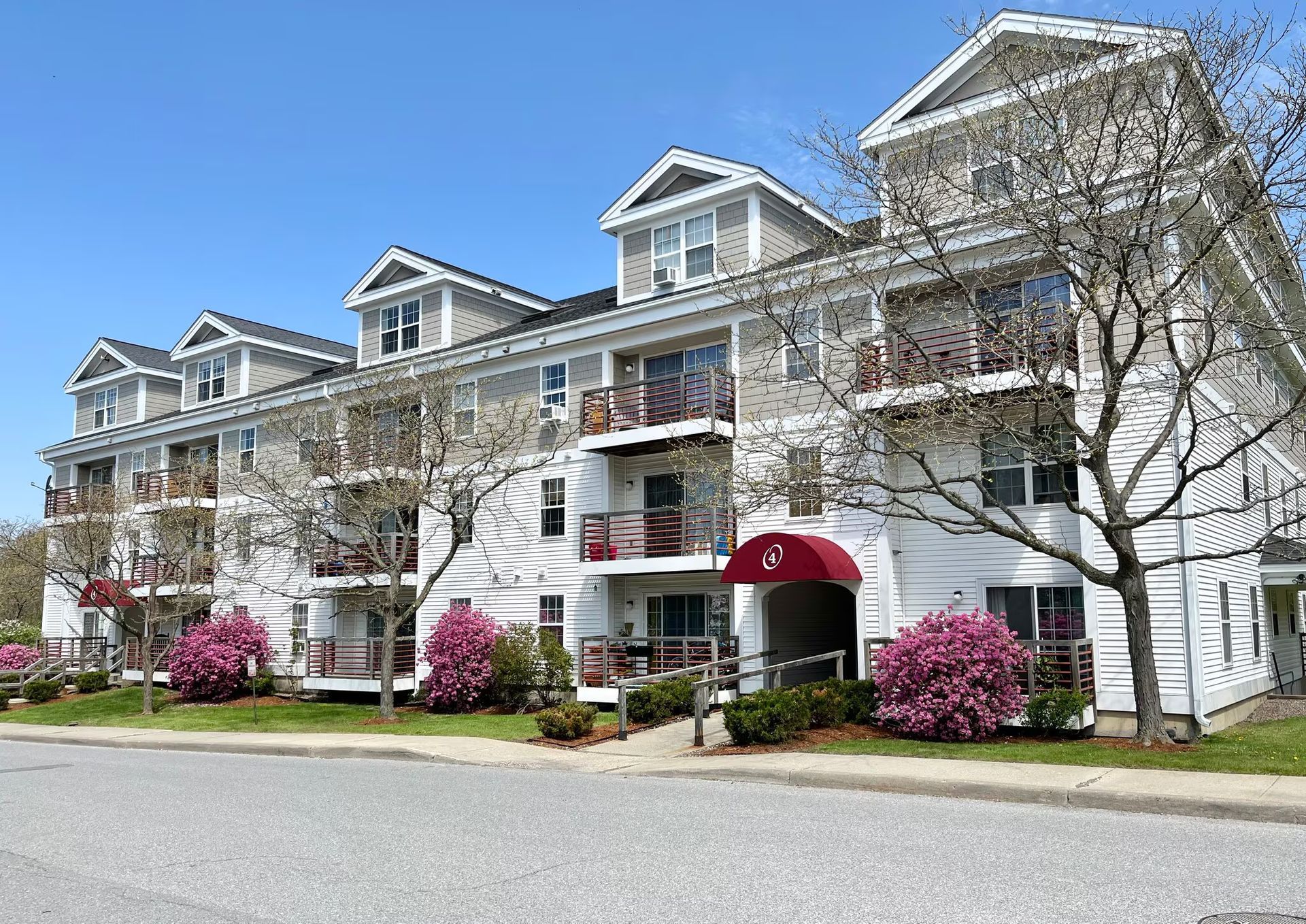 A large white building with balconies and trees in front of it