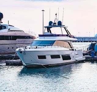 White luxury yacht docked at a marina beside other boats on calm water