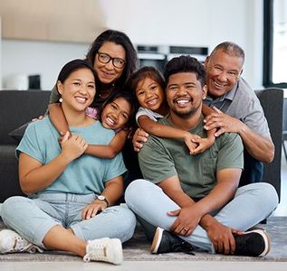 Smiling family sitting on the floor together in a bright living room, hugging and posing close together