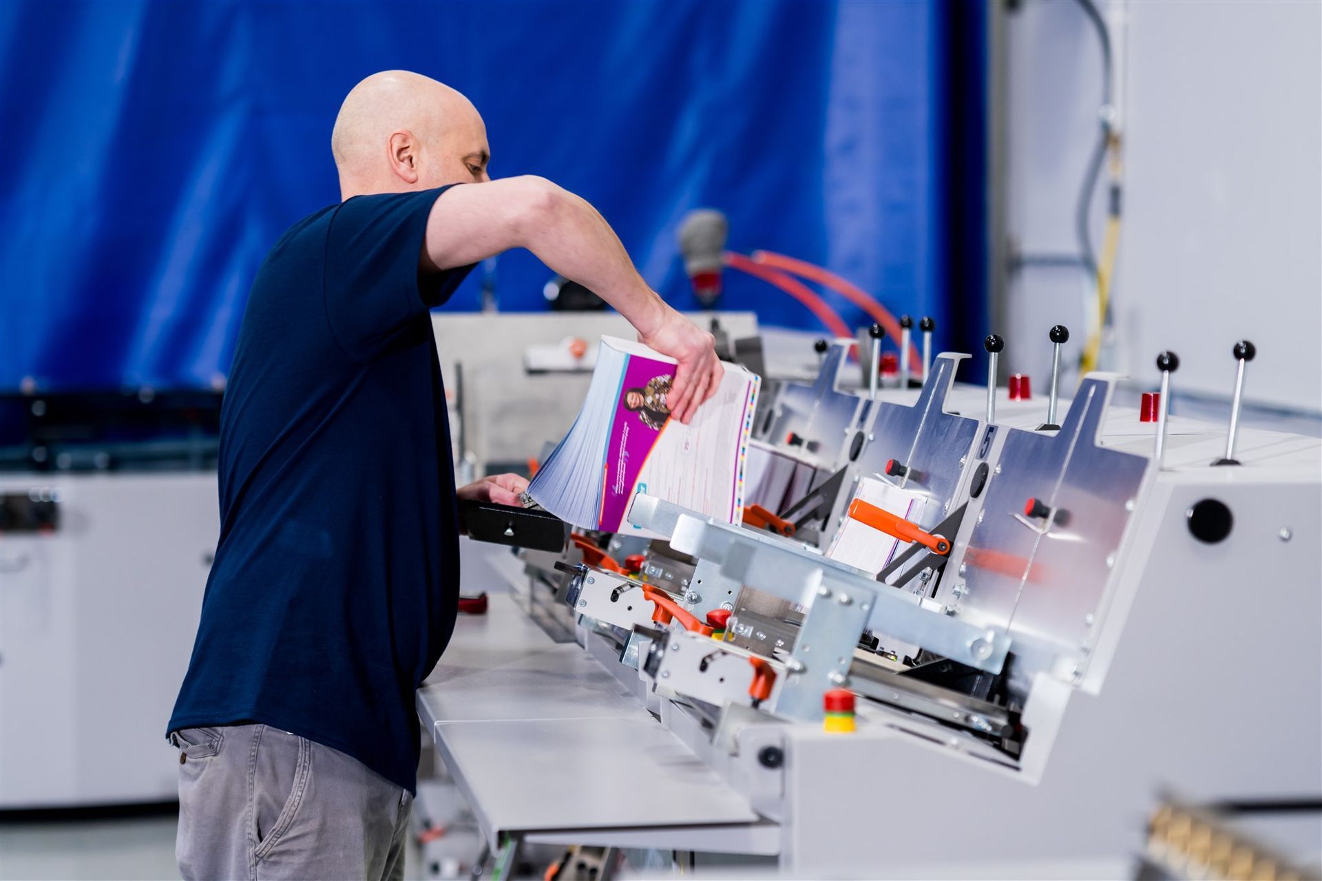 Worker loading materials into an industrial machine on a factory floor