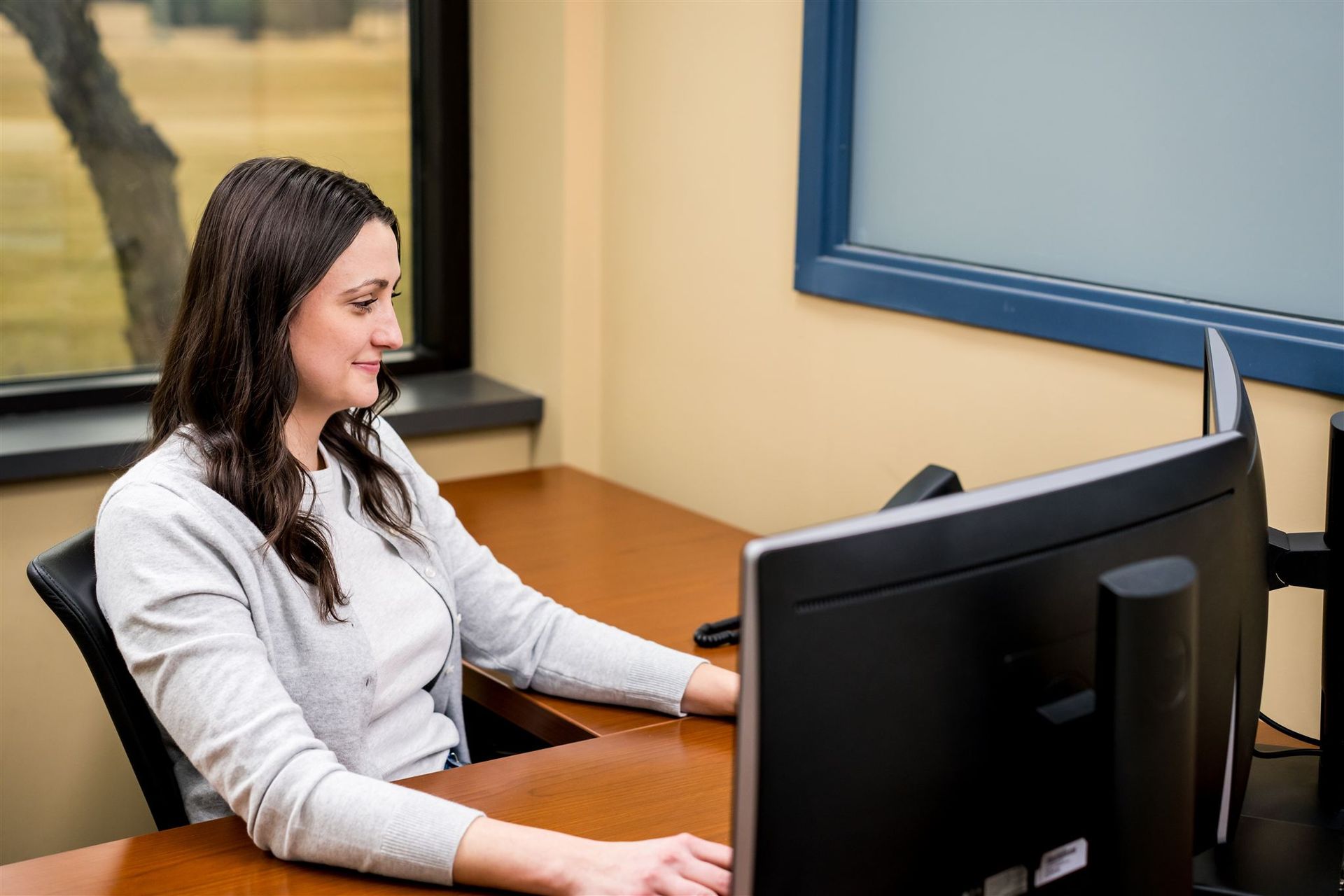 Woman using a desktop computer at a desk in an office setting