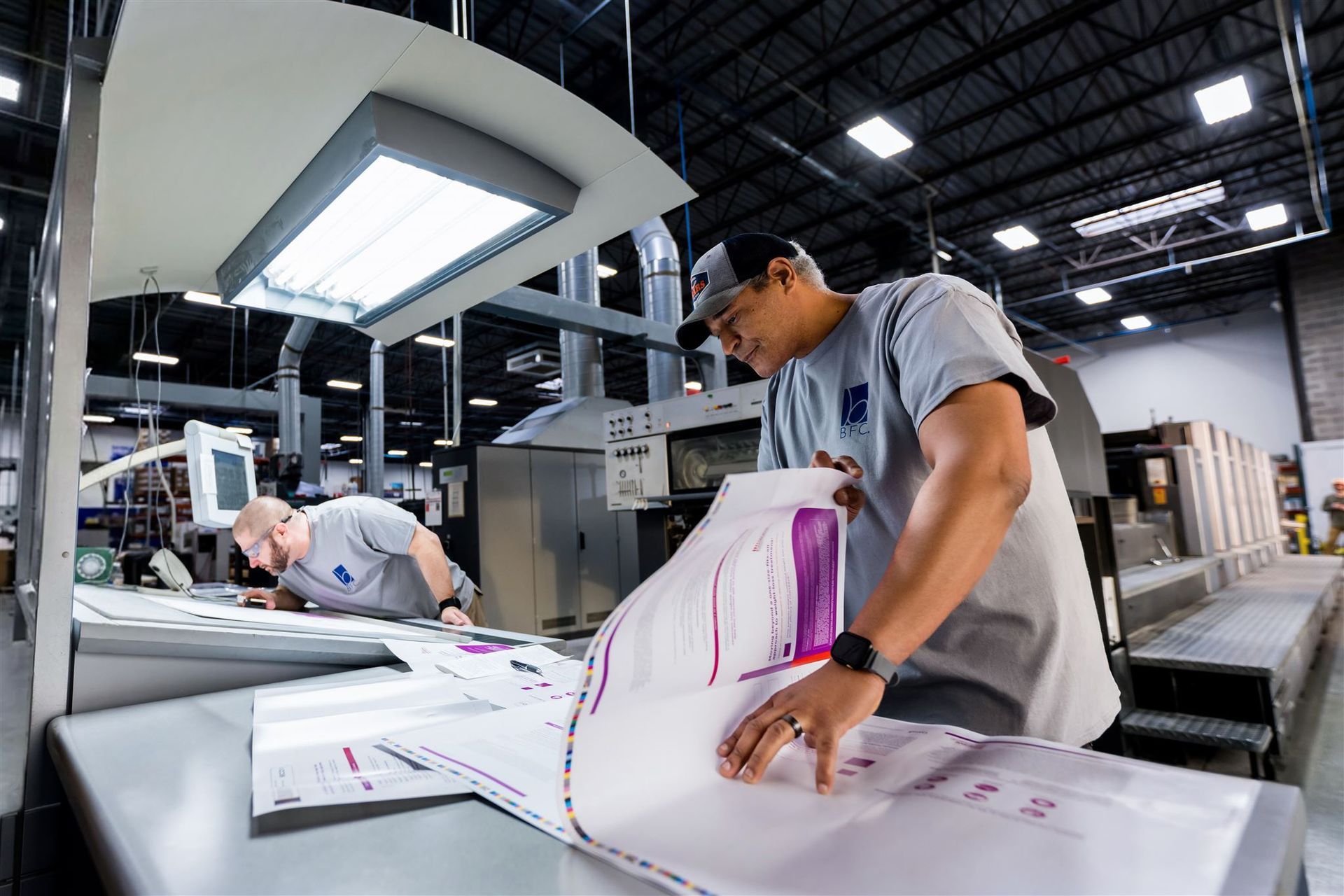 Printing technician inspecting large sheets in an industrial print shop