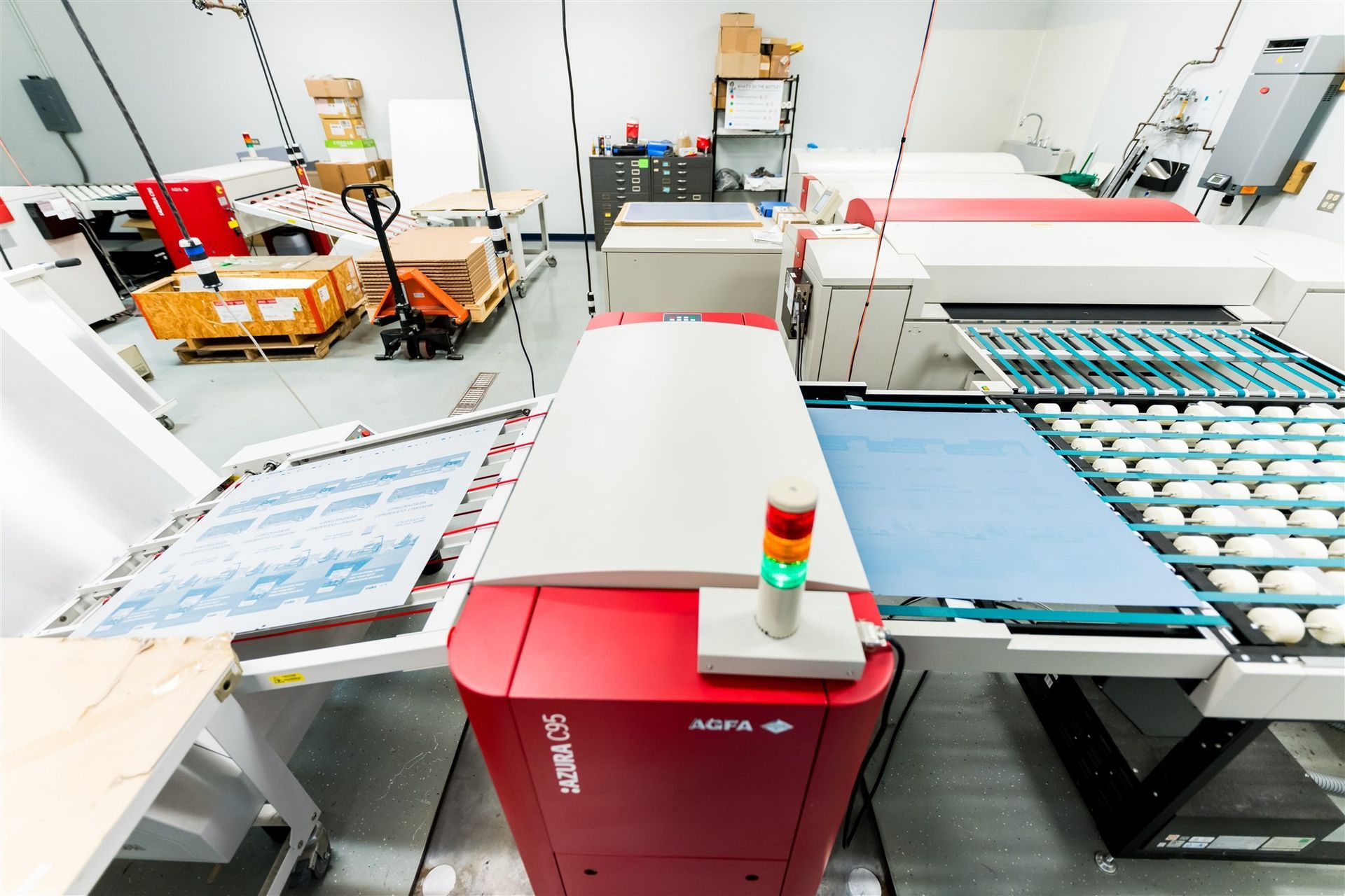 Automated factory line with red machine and conveyor belts moving stacked trays through a clean production area