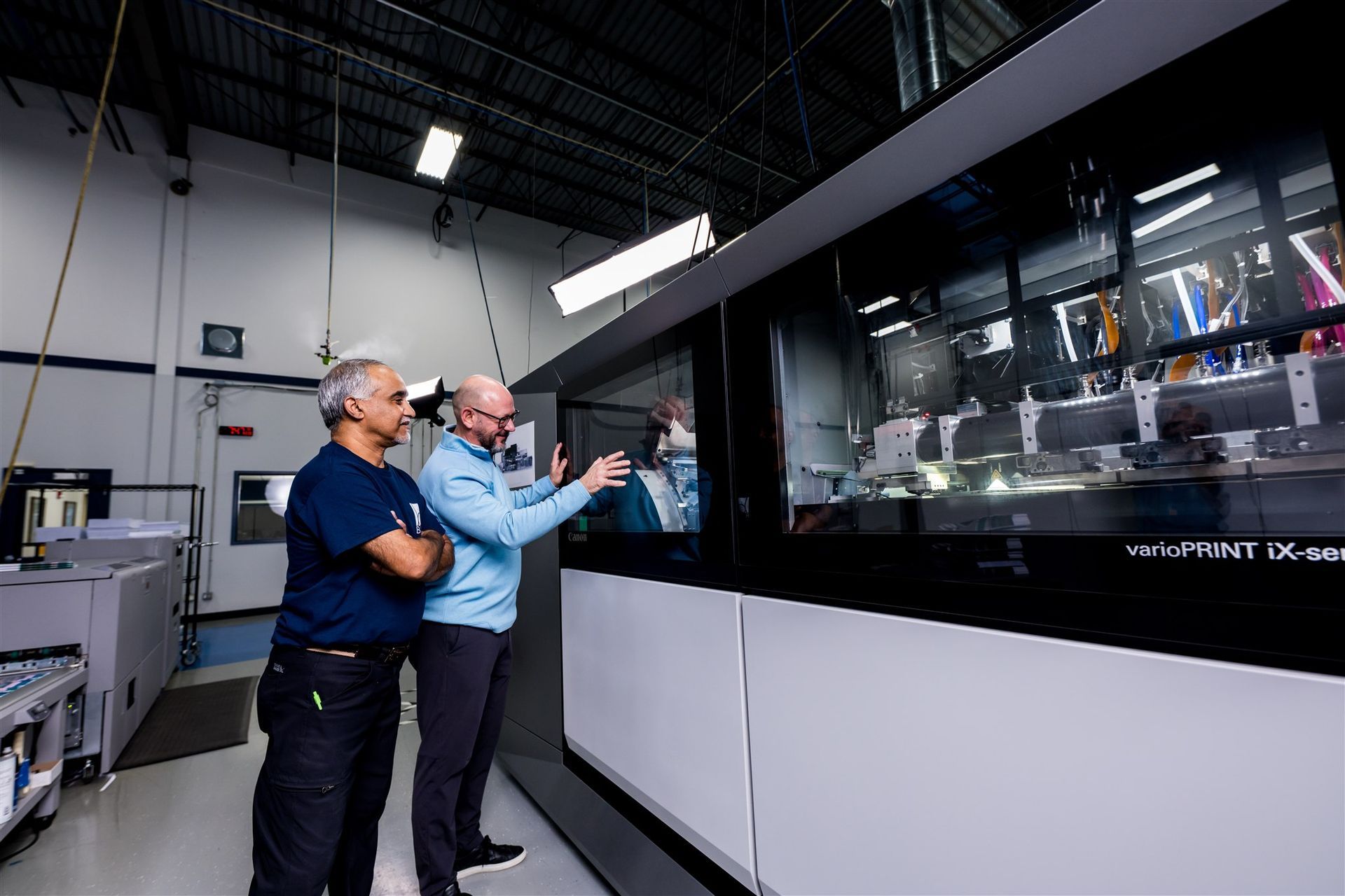 Two workers examining a large industrial machine in a factory shop floor