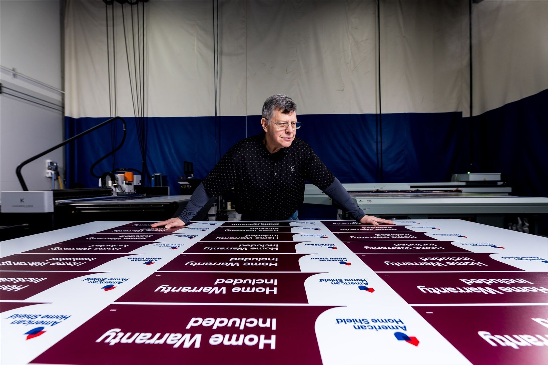 Man laying out large maroon and white printed sheets in a workshop