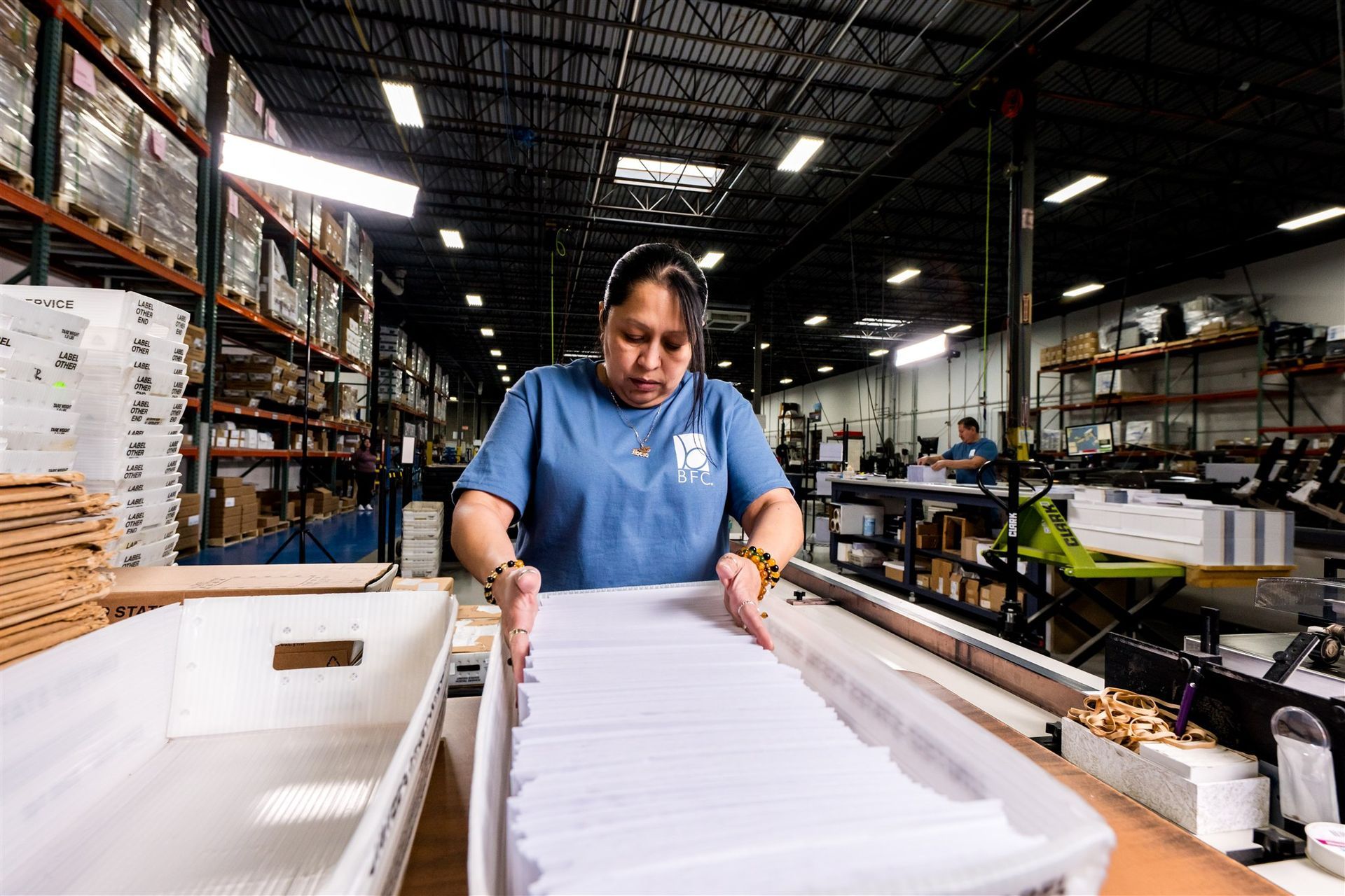 Worker in a warehouse stacking white paper on a conveyor line