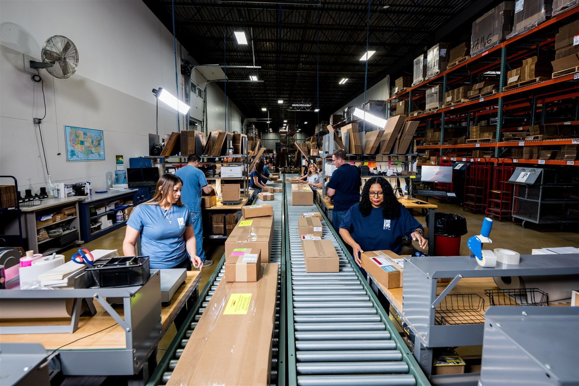 Factory workers assembling packages on a conveyor line in a warehouse