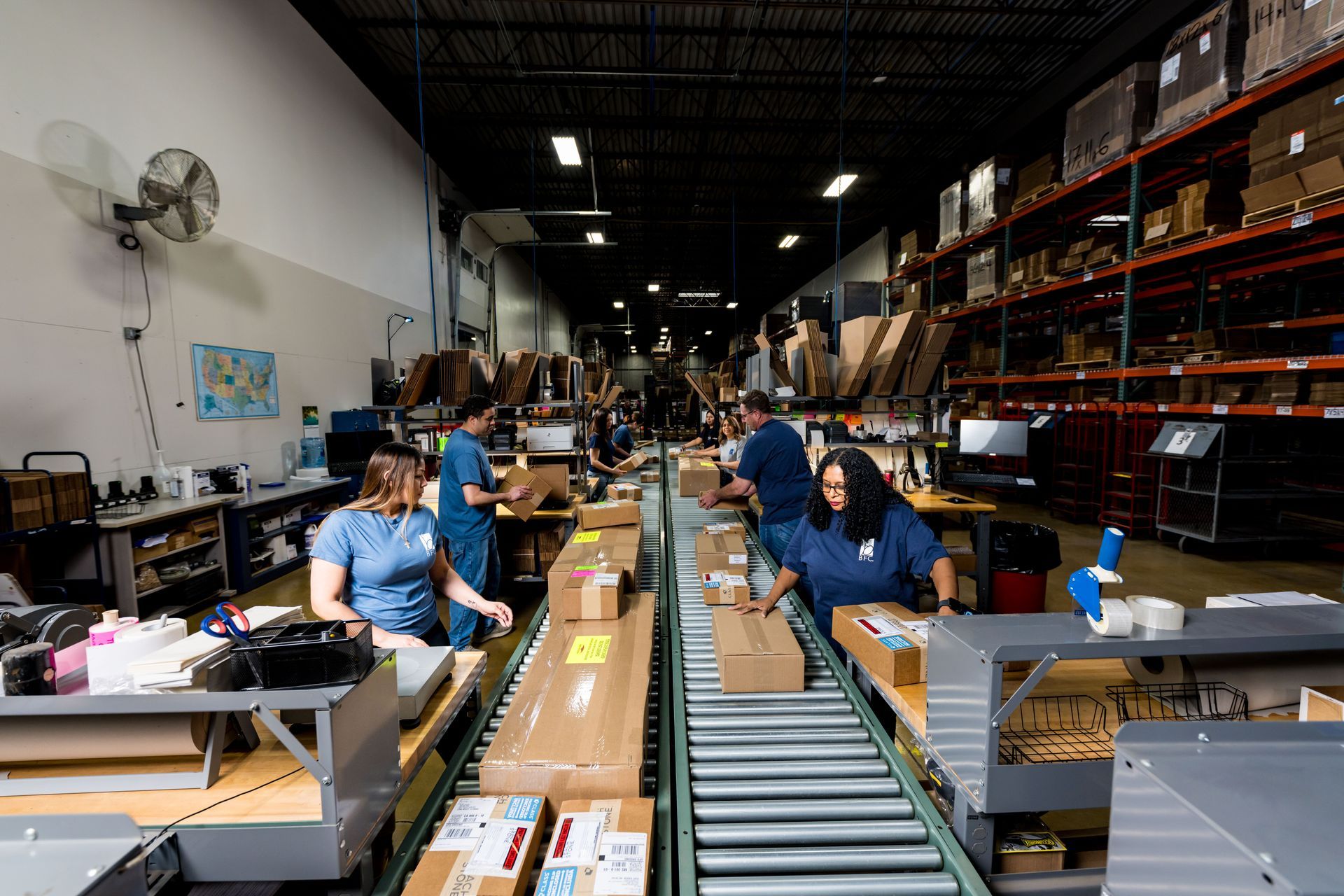 Workers sorting packages on conveyor belts in a warehouse aisle