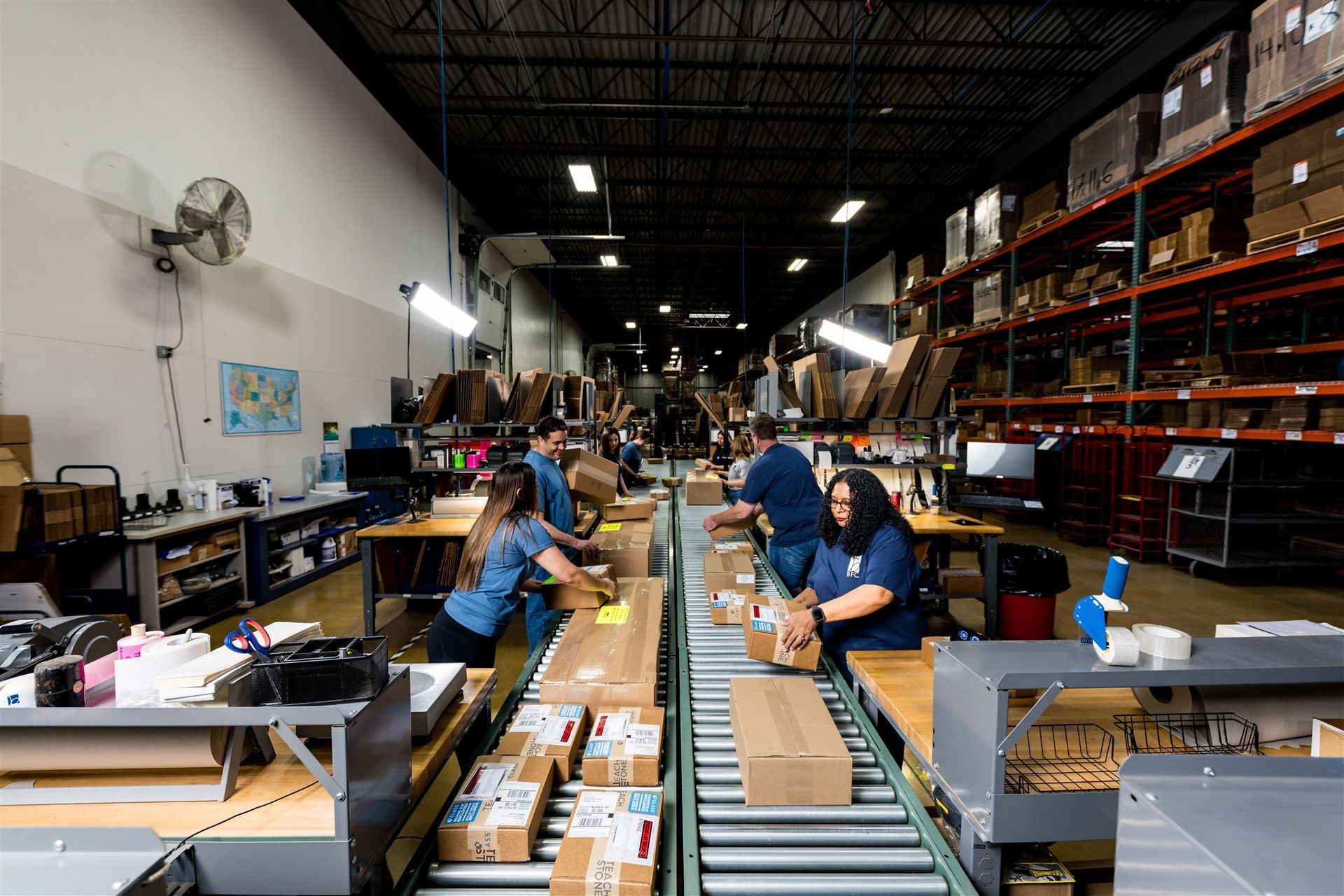 Warehouse workers sorting packages on conveyor belts in a large industrial storage space
