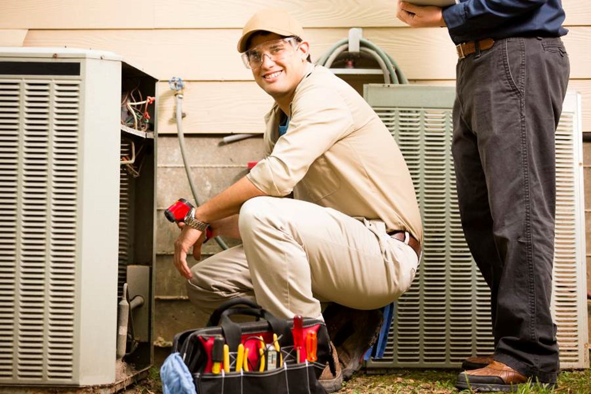 Certified AC Services team member is providing AC maintenance service in the Greater Orlando area. Two men are repairing an air conditioner in the greater Orlando area