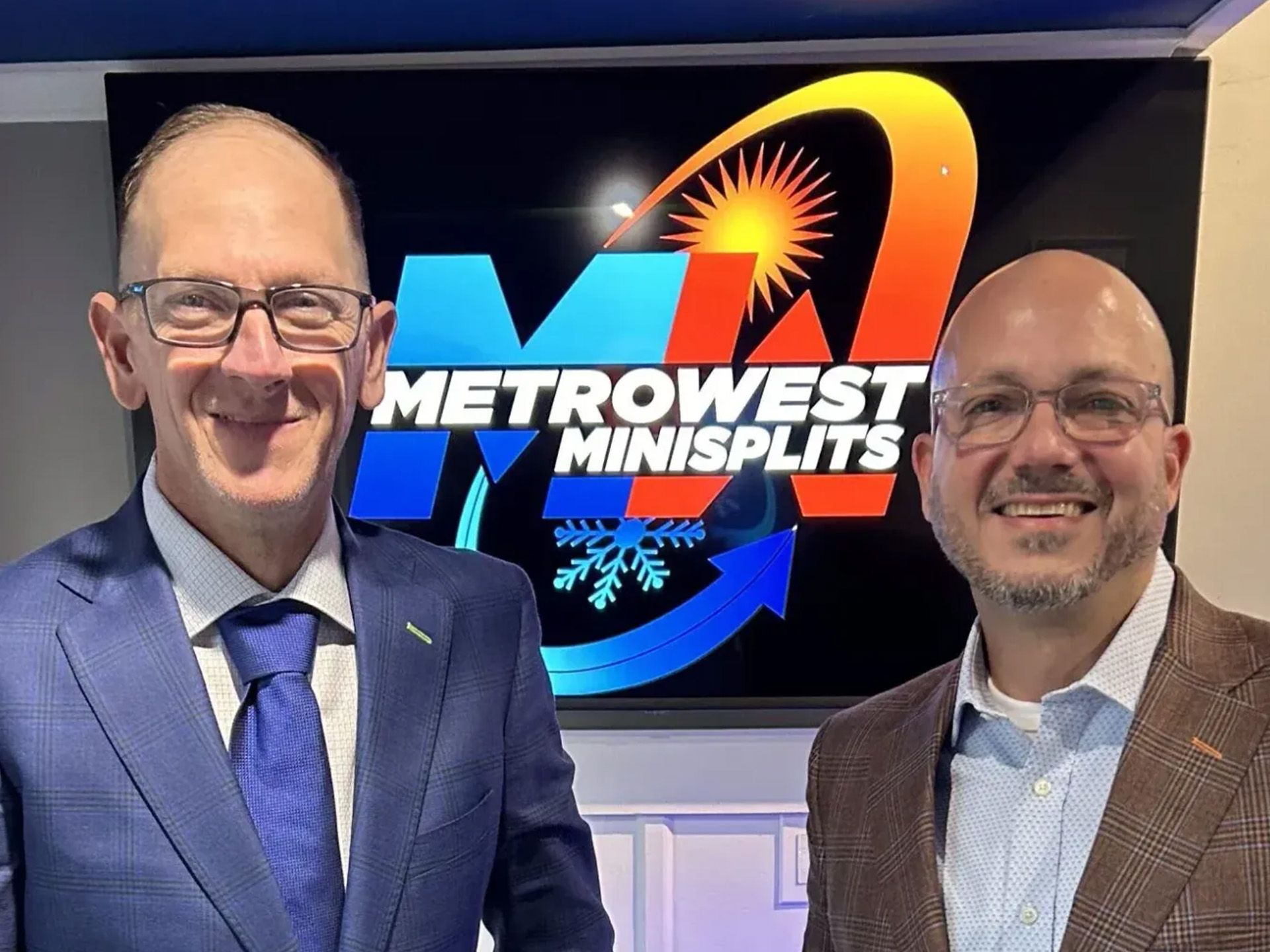 Two men are standing in front of a screen that says metrowest minisplits