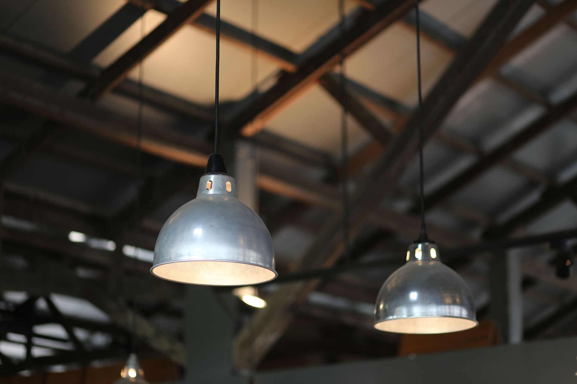 Two silver hanging pendant lights in a dark industrial ceiling interior