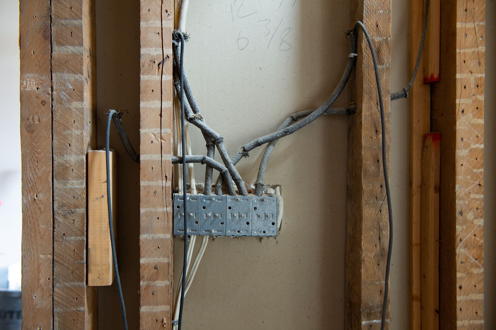 Exposed electrical wiring and a metal junction box mounted in a wall opening during construction
