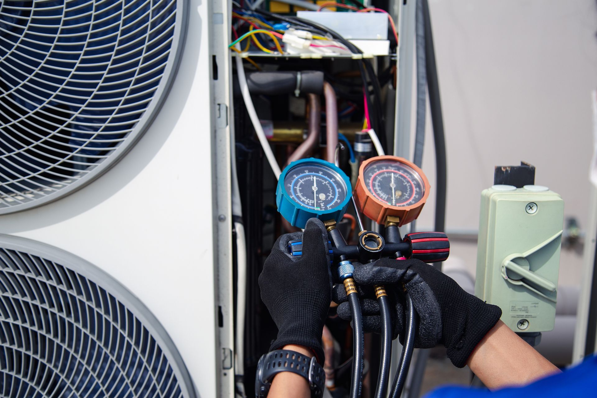 HVAC technician using gauges on an air conditioning unit.